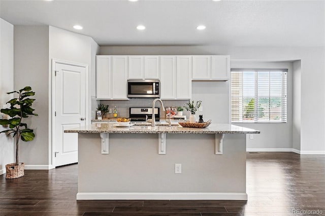 3548 Swabuck Pl, Castle Rock, CO 80109 - kitchen with appliances with stainless steel finishes, light stone counters, dark wood-style flooring, a breakfast bar area, and recessed lighting