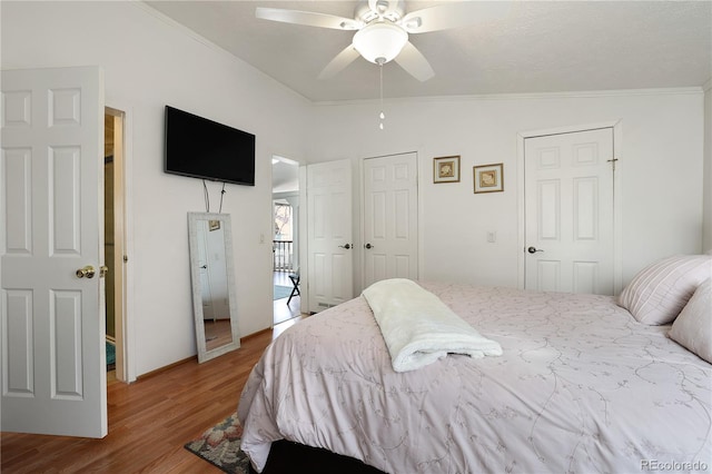 bedroom featuring lofted ceiling, ceiling fan, hardwood / wood-style flooring, two closets, and crown molding