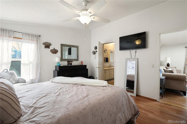 bedroom featuring ensuite bath, light wood-type flooring, ceiling fan, and a textured ceiling