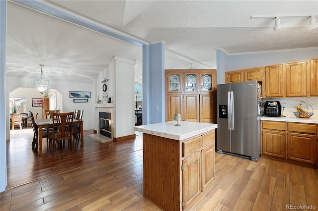 kitchen featuring a chandelier, stainless steel fridge with ice dispenser, a center island, decorative light fixtures, and lofted ceiling