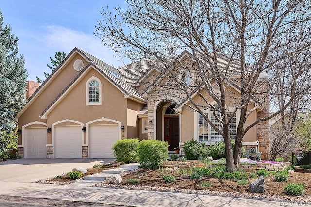 traditional-style home featuring a garage, stucco siding, driveway, and stone siding