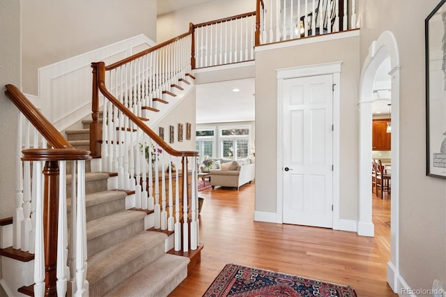 foyer entrance featuring baseboards, a towering ceiling, wood finished floors, and stairway