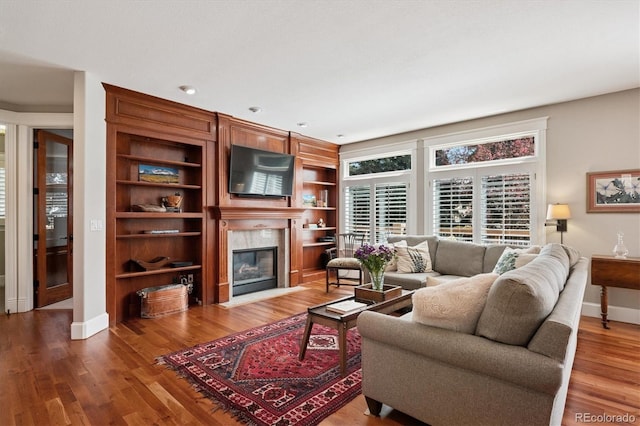 living area with a high end fireplace, baseboards, and wood finished floors