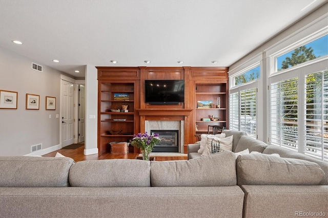 living room with recessed lighting, visible vents, wood finished floors, and a high end fireplace
