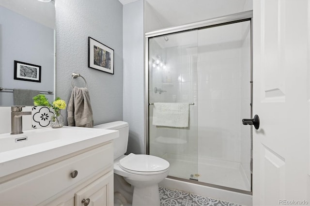 bathroom with vanity, a textured wall, a shower stall, and toilet
