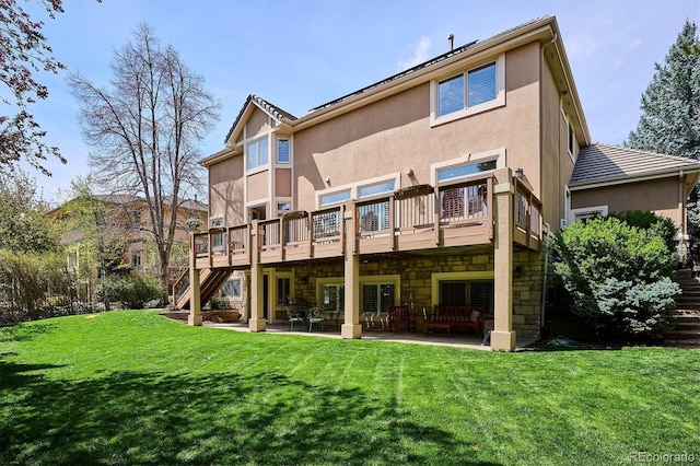 back of property featuring a deck, a patio, stucco siding, a yard, and stairway