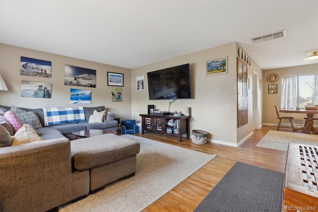 living room featuring baseboards, visible vents, and wood finished floors