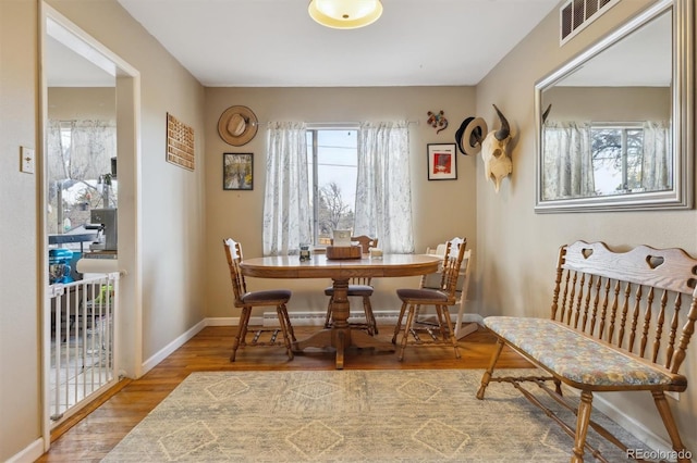 dining space featuring plenty of natural light, baseboards, visible vents, and wood finished floors