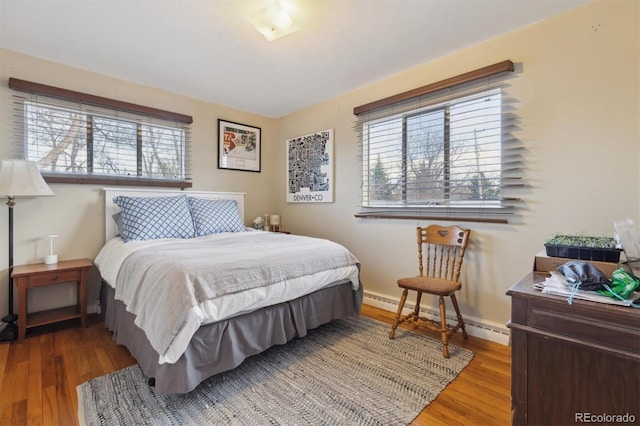 bedroom featuring a baseboard radiator, wood finished floors, and baseboards
