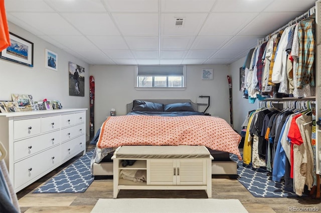 bedroom with a drop ceiling, visible vents, and light wood-type flooring