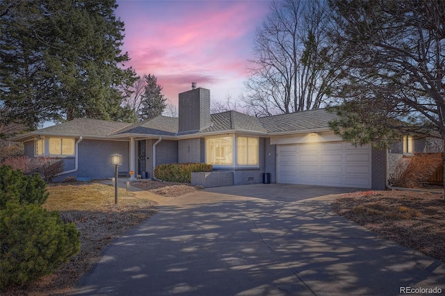 single story home with brick siding, a chimney, concrete driveway, and an attached garage