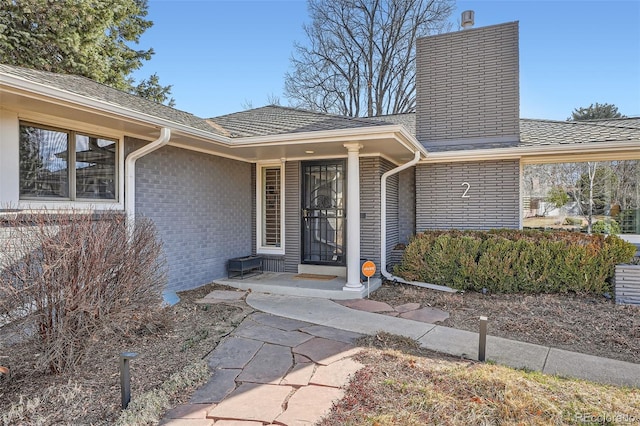 doorway to property with brick siding and a chimney