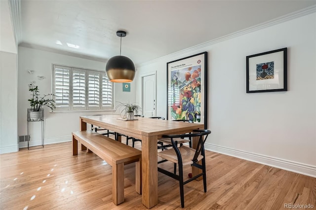 dining room featuring light wood-type flooring, baseboards, visible vents, and ornamental molding