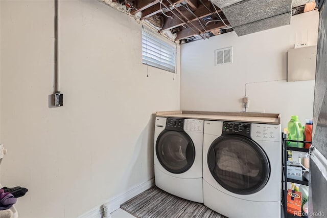 washroom with visible vents, washing machine and dryer, and baseboards