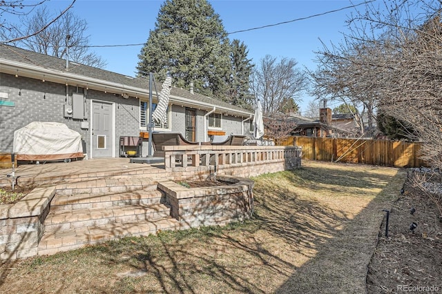 back of house featuring brick siding, a wooden deck, and fence