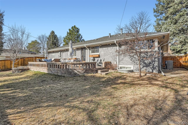 rear view of property with brick siding, a lawn, cooling unit, a deck, and a fenced backyard