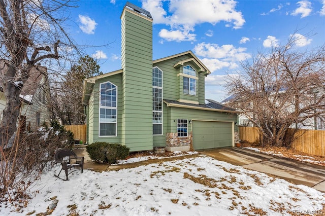 view of front of home featuring a garage, concrete driveway, fence, and a chimney