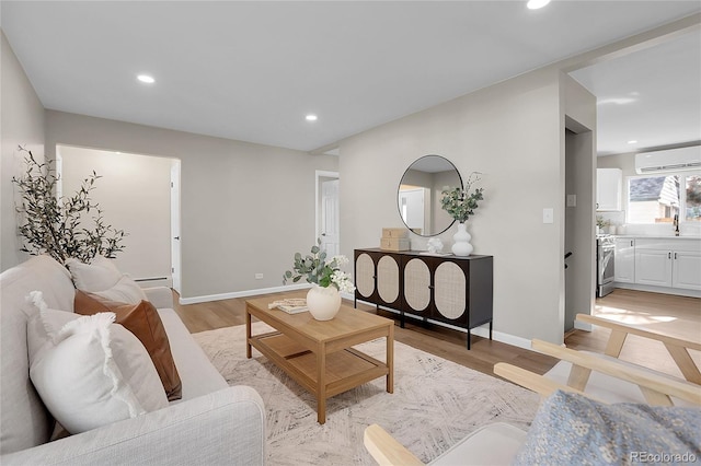 living room with light hardwood / wood-style floors, sink, and a wall mounted AC