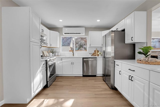 kitchen with white cabinets, appliances with stainless steel finishes, sink, and a wall mounted air conditioner