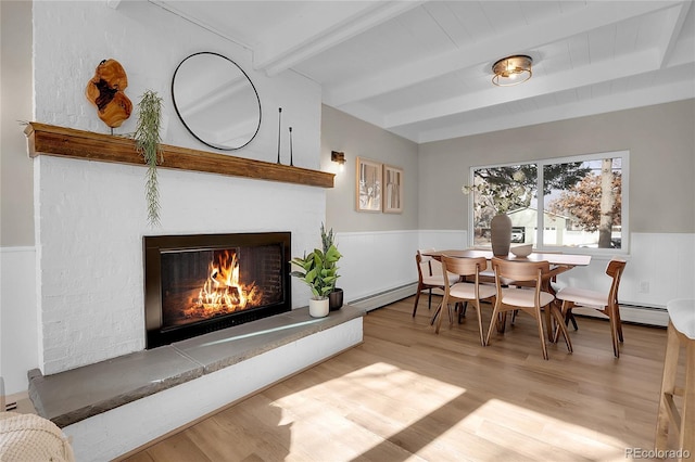 dining room featuring beam ceiling, light wood-type flooring, and a baseboard radiator