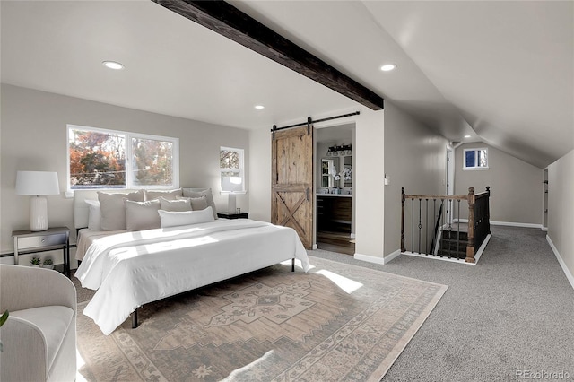 carpeted bedroom with ensuite bath, a barn door, and lofted ceiling with beams