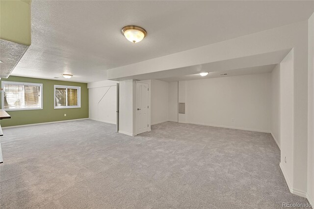 3406 Purcell St, Brighton, CO 80601 - below grade area with light carpet, baseboards, and a textured ceiling