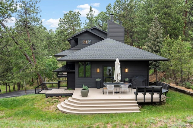 28833 Western Dr, Evergreen, CO 80439 - back of house with roof with shingles, a chimney, a wooden deck, and a lawn