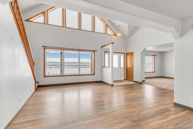 unfurnished living room with wood-type flooring and high vaulted ceiling