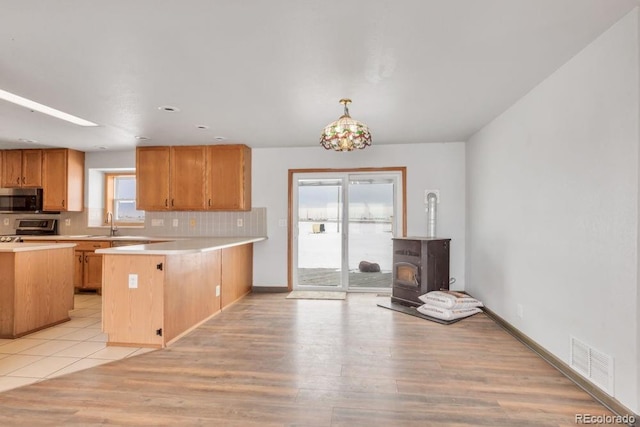 kitchen featuring stove, decorative light fixtures, a wealth of natural light, and kitchen peninsula