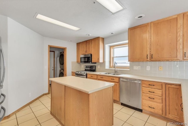 kitchen with stacked washer / drying machine, sink, a center island, appliances with stainless steel finishes, and decorative backsplash