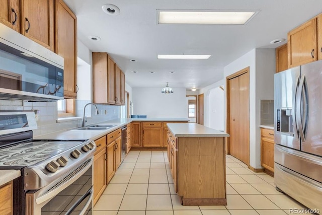 kitchen with sink, decorative light fixtures, a kitchen island, stainless steel appliances, and decorative backsplash