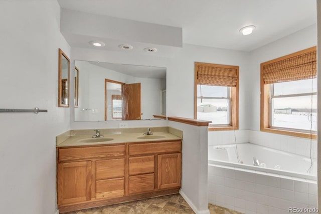 bathroom featuring tiled tub and vanity