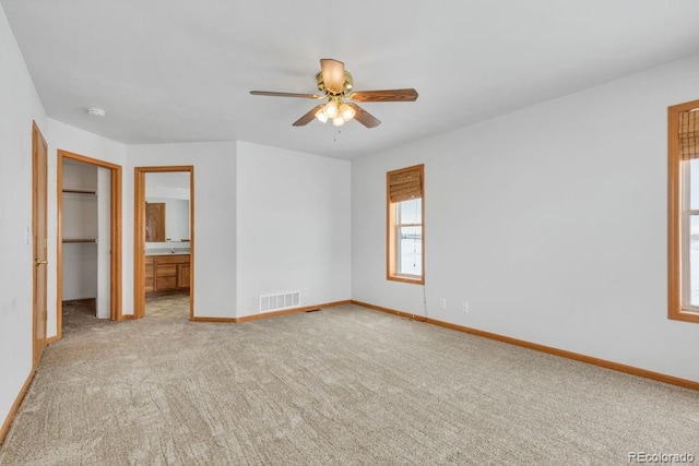 unfurnished bedroom with ensuite bathroom, light colored carpet, and ceiling fan