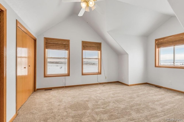 additional living space with a healthy amount of sunlight, vaulted ceiling, and light carpet