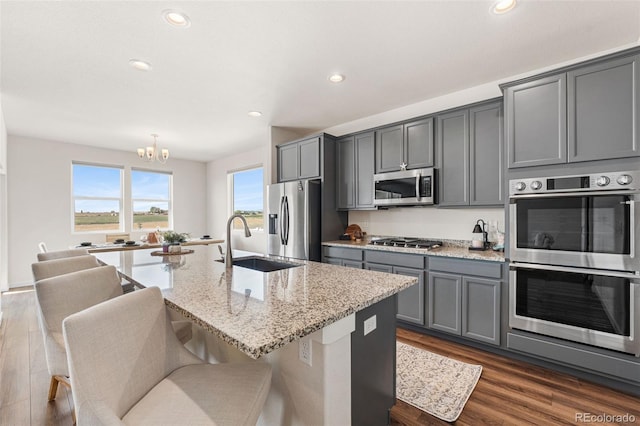 kitchen featuring a sink, stainless steel appliances, gray cabinets, dark wood-type flooring, and a chandelier