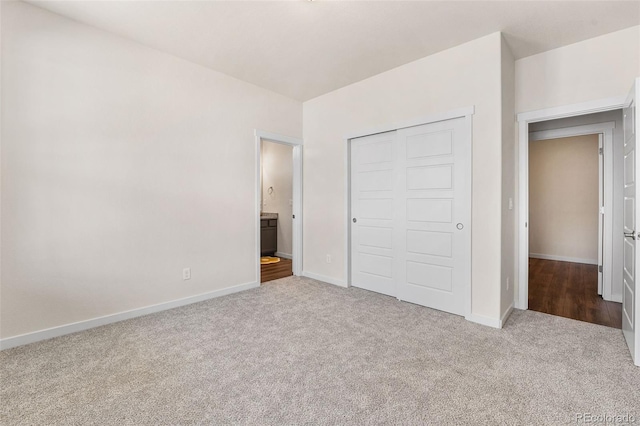 unfurnished bedroom with ensuite bathroom, carpet floors, baseboards, and a closet
