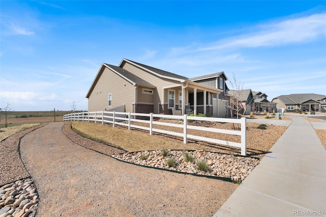 view of home's exterior with concrete driveway, a fenced front yard, and a residential view