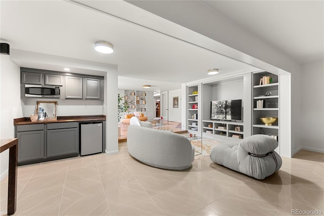 living room with built in shelves and light tile patterned floors