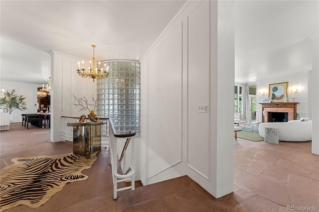 corridor featuring an inviting chandelier, stone tile flooring, and ornamental molding