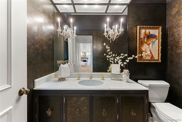 bathroom with a notable chandelier, vanity, and toilet