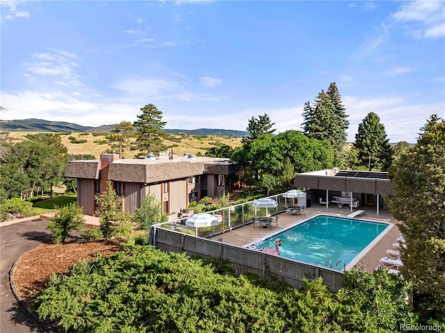 view of pool featuring a mountain view, a patio, a fenced in pool, and fence