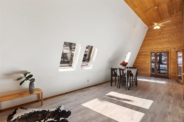 dining area featuring wooden walls, a ceiling fan, wood finished floors, high vaulted ceiling, and wood ceiling