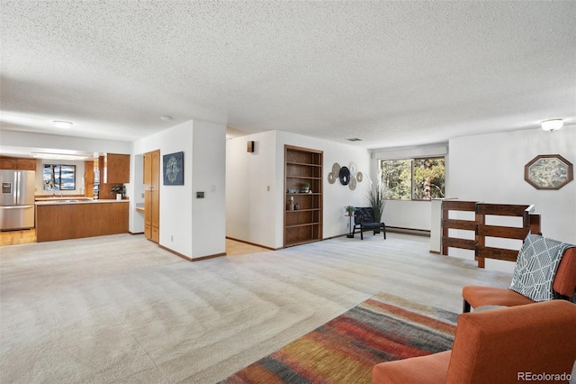 living area featuring plenty of natural light, light colored carpet, and a textured ceiling