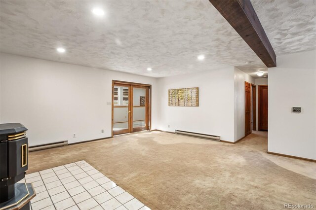 unfurnished living room with a baseboard radiator, baseboards, light colored carpet, and a wood stove