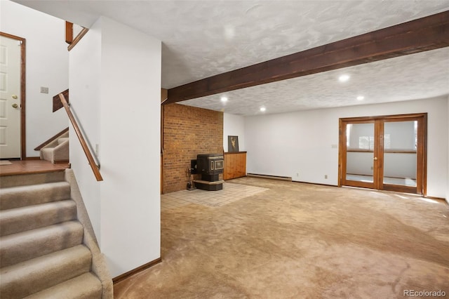 basement featuring stairs, carpet floors, a baseboard radiator, baseboards, and a wood stove