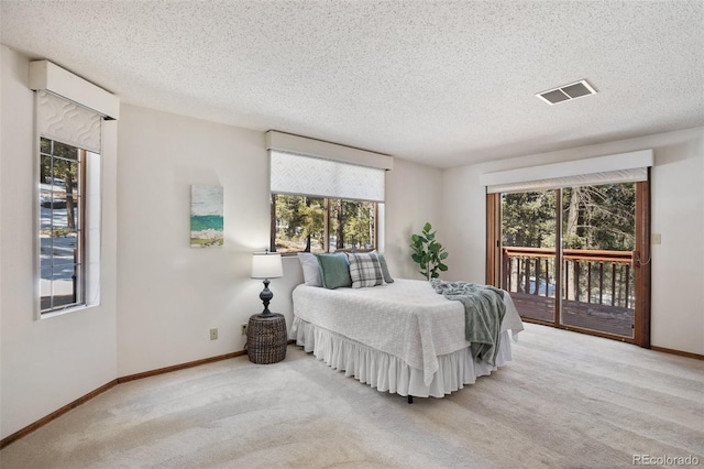 bedroom featuring access to exterior, visible vents, carpet flooring, and a textured ceiling