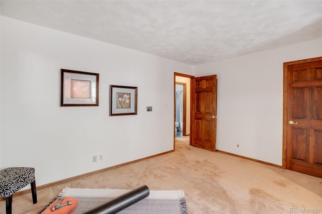 exercise area with baseboards, a textured ceiling, and light carpet