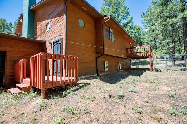 view of side of home with a chimney, fence, a deck, and a gate