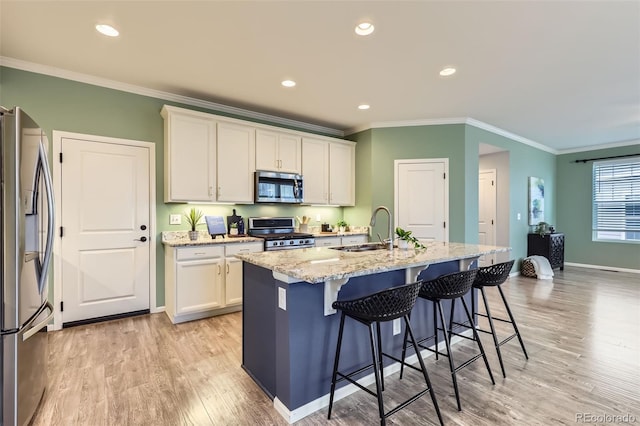 17859 E 108th Pl, Commerce City, CO 80022 - kitchen featuring white cabinets, a sink, light wood-type flooring, appliances with stainless steel finishes, and ornamental molding