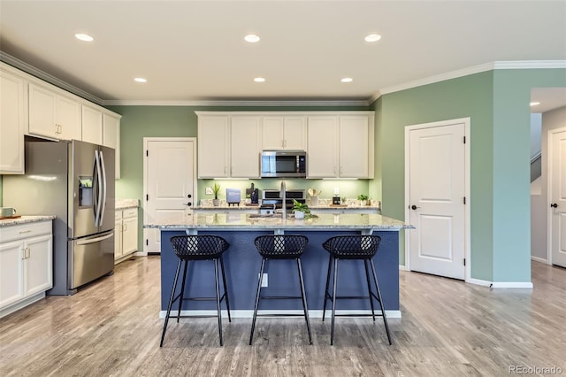 17859 E 108th Pl, Commerce City, CO 80022 - kitchen featuring light wood finished floors, stainless steel appliances, white cabinets, a kitchen bar, and ornamental molding